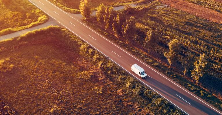 Luchtfoto van bestelwagen op de weg in de zomerzonsondergang